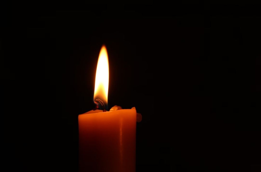 Red candle lit against a black background. 